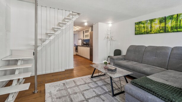 A modern living room with a grey sofa, a coffee table, and a staircase. - Lodge of Sardona (Glarus Süd)
