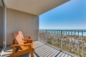 A balcony with wooden chairs and a view of the beach.