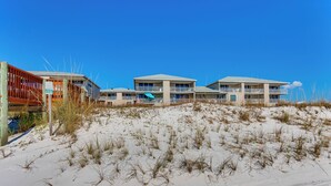 A beachfront hotel with multiple buildings, sandy terrain, and sparse vegetation. - Direct Sand Access! Family Pensacola Beach Retreat (Pensacola Beach)