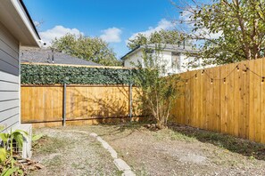 Un jardin avec une clôture en bois, un petit arbre et un chemin de gravier.