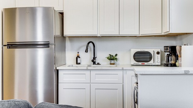 A compact kitchen with white cabinets, a stainless steel refrigerator, a microwave, and a coffee maker. - Walk to Park: Dog-friendly Retreat in Pflugerville (Pflugerville)