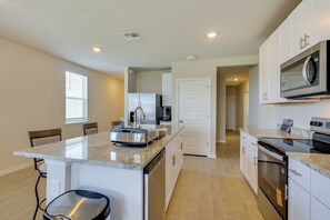 Una cocina moderna con una isla central, electrodomésticos integrados y una distribución ordenada.