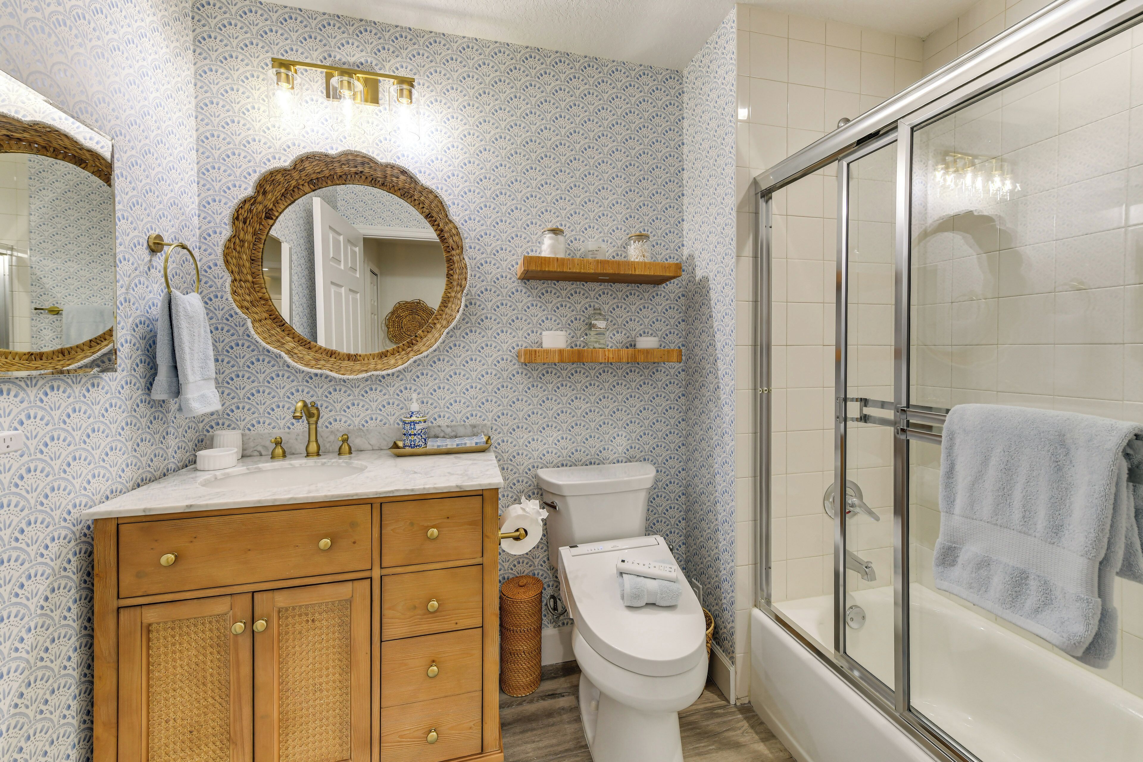 Ein Badezimmer mit Holzwaschtisch, Toilette, Dusche mit Glastür und dekorativen Wandschränken.