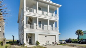 A two-story white building with a balcony on the second floor, a garage, and a clear blue sky. - Oceanfront Retreat in Flagler Beach! Bright Apt (Flagler Beach)