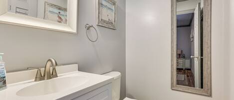 A bathroom with a white sink, a toilet, and a mirror.