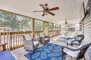 A covered porch with wicker furniture, a ceiling fan, and a blue patterned rug. - Play & Unwind, Oak Island Home < 2 Mi to Beach! (Oak Island)