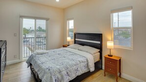 A bedroom with a bed, bedside tables, a dresser, a window, and a balcony. - Explore the OC Coast! Midway City Home w/ Yard (Midway City)
