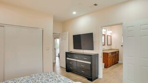 A bedroom with a bed, a dresser, a TV, and a bathroom with a sink and mirror. - Explore the OC Coast! Midway City Home w/ Yard (Midway City)