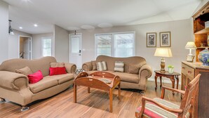 A living room with two sofas, a wooden coffee table, and a wooden chair. There are two windows with blinds, a door, and a lamp on a side table. - Hike & Relax: Tranquil Wooded Escape in Hockley (Hockley)