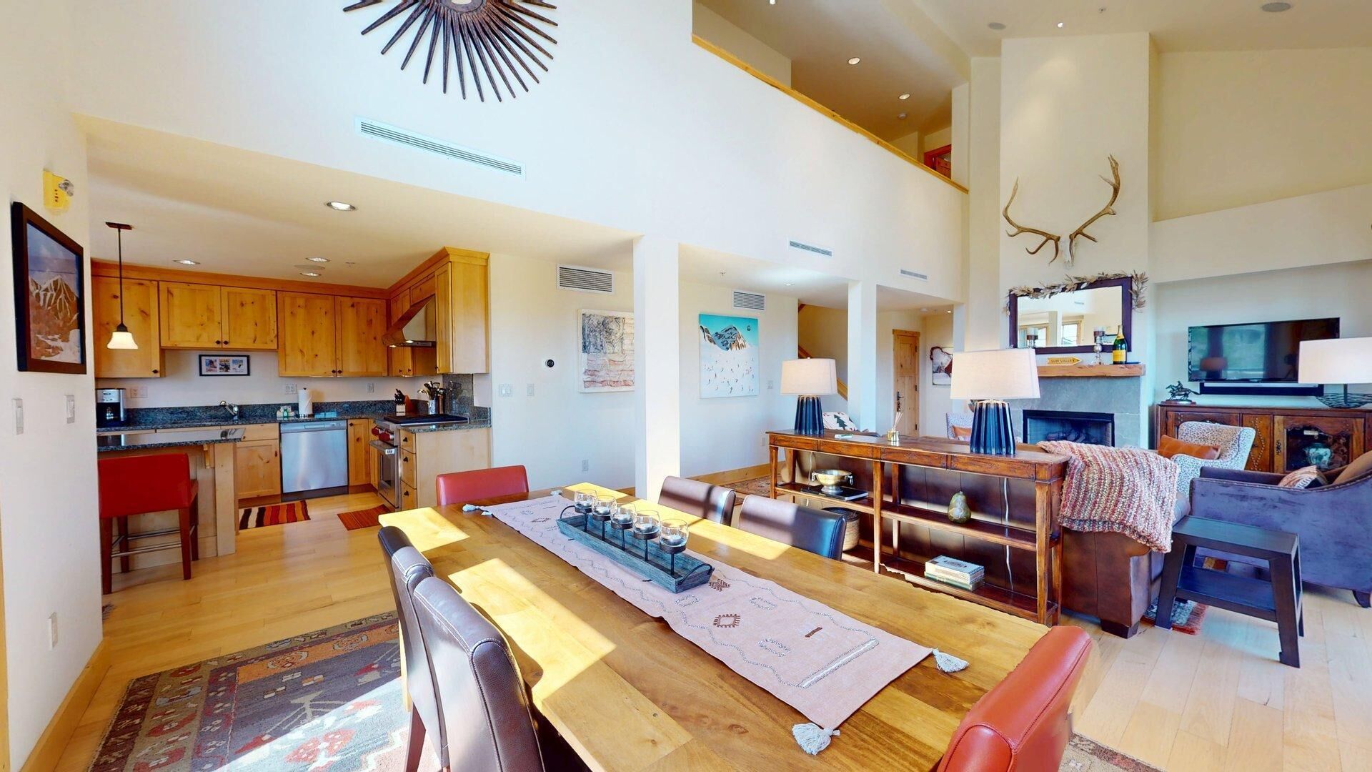 A spacious living area with a wooden dining table, a sofa, and a fireplace.