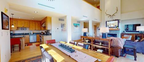 A spacious living area with a wooden dining table, a sofa, and a fireplace.