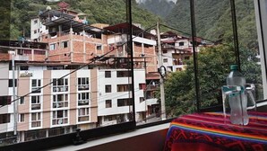 A view of a mountainous area with buildings, including a multi-story structure with balconies and a sign that reads "Maidland." - Raymi MachuPicchu (Aguas Calientes)