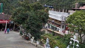 A courtyard with a fountain, surrounded by trees and buildings with balconies. - Raymi MachuPicchu (Aguas Calientes)
