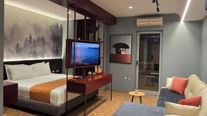 Une chambre d’hôtel moderne équipée d’un lit, d’une télévision, d’un canapé et d’un coin repas.