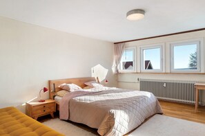 Ein Schlafzimmer mit einem Bett, Nachttischen, einem Fenster und einer Heizung.