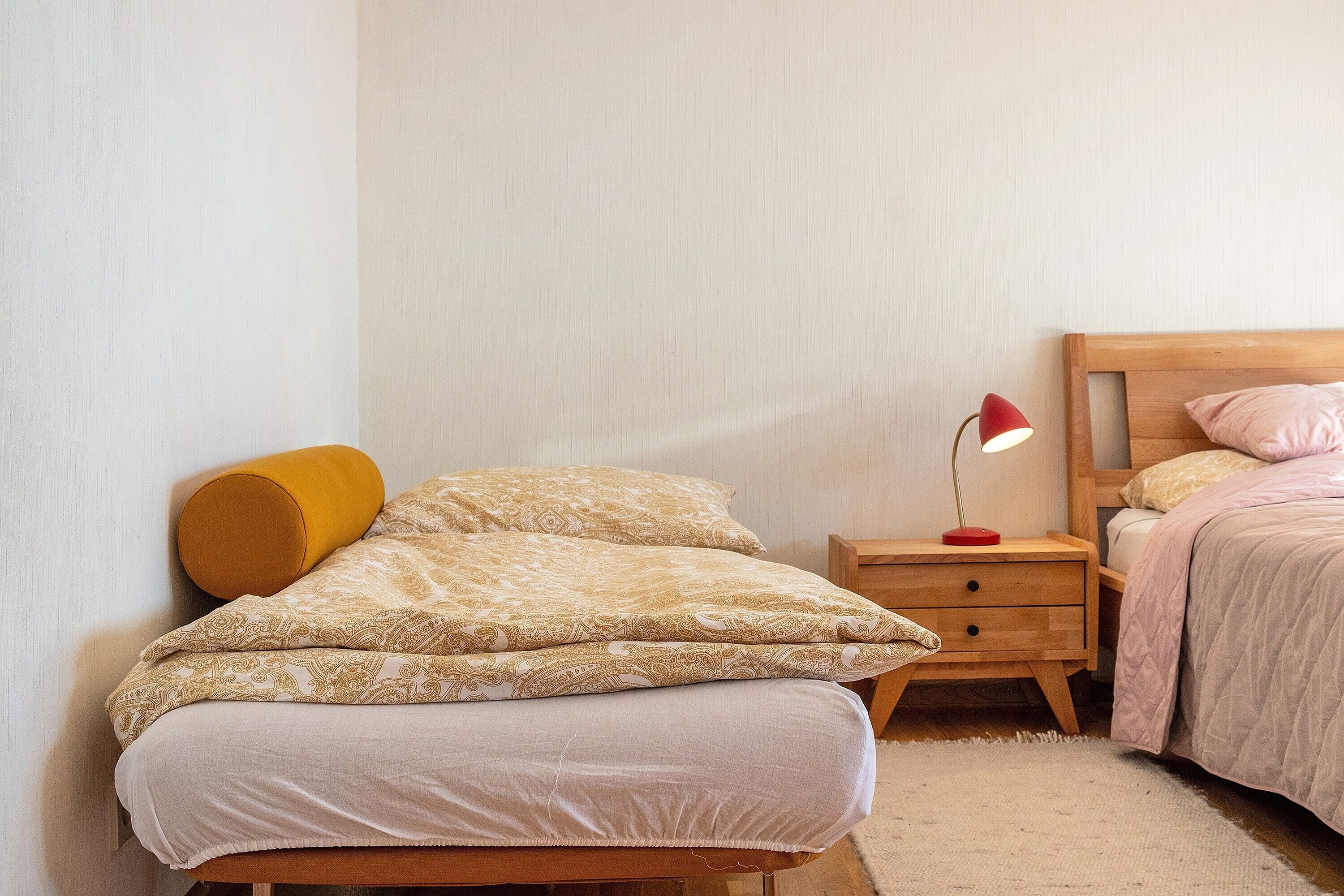 Ein Schlafzimmer mit einem Bett, einem Nachttisch, einer Lampe und einem Beistelltisch.