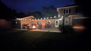 A residential backyard with a fire pit, outdoor seating, and string lights. - Hometown Haven
quiet•peaceful•cozy (Hancock)