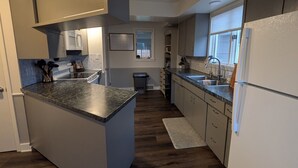 A modern kitchen with a central island, white cabinets, a built-in microwave, and a stainless steel sink. - Hometown Haven
quiet•peaceful•cozy (Hancock)