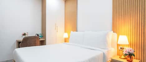 Habitación de hotel con una cama grande, lámparas de noche, un escritorio con silla y un panel de pared de madera.