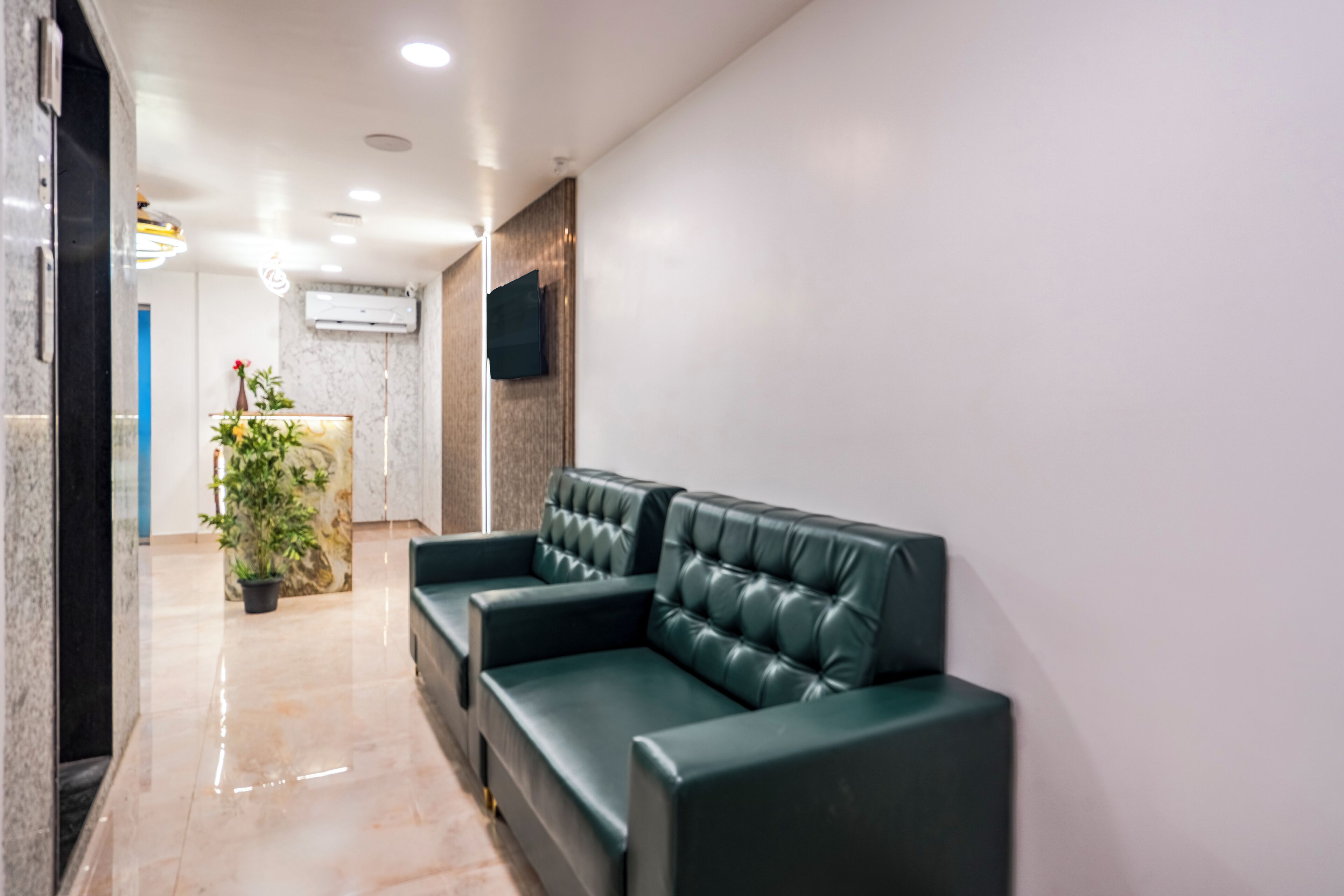Eine moderne Lobby mit einer Rezeption, einem grünen Ledersofa und einem Blumentopf.