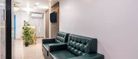 Eine moderne Lobby mit einer Rezeption, einem grünen Ledersofa und einem Blumentopf.