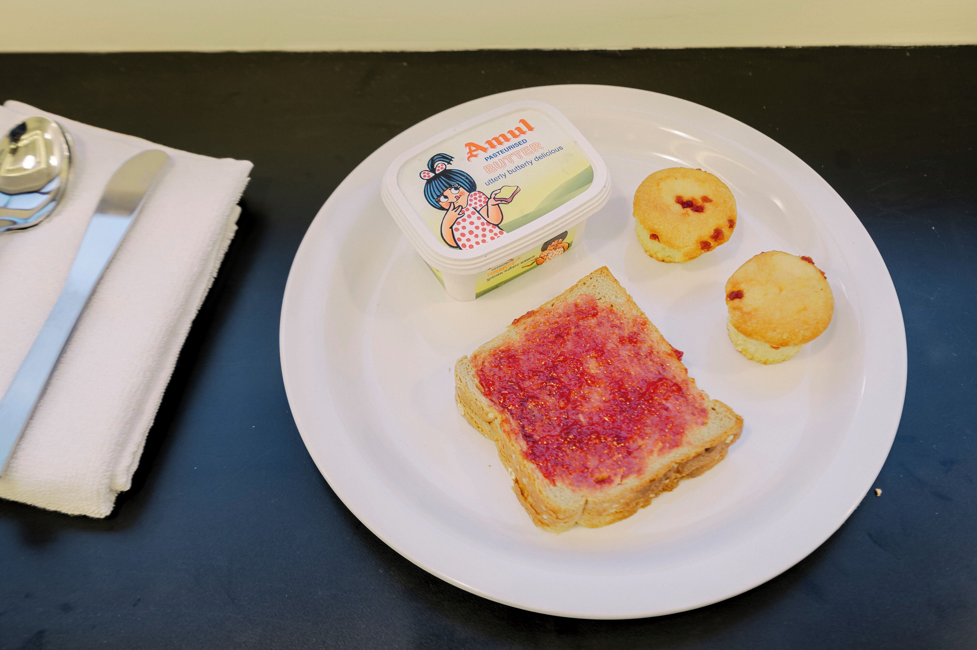 A plate with toast, butter, and two small pastries on a table.