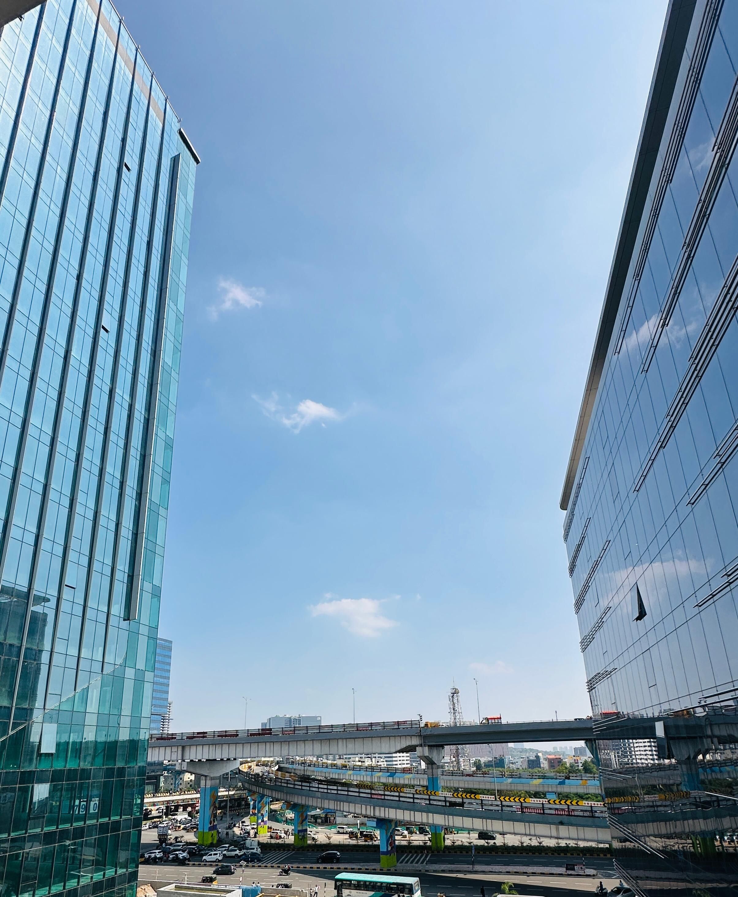 A modern building with a glass facade and a view of an elevated road with vehicles.