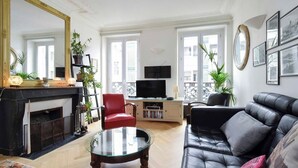 Uma sala de estar com lareira, televisão, sofá e mesa de centro.