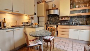 Uma cozinha com uma mesa redonda de mármore, cadeiras de madeira e um forno embutido.