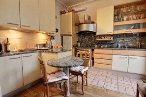 Una cocina con una mesa redonda de mármol, sillas de madera y un horno empotrado.