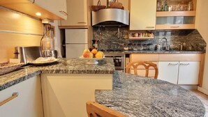 Uma cozinha moderna com bancadas de granito, fogão embutido e área de refeições com mesa redonda e cadeiras.