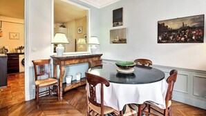 A dining area with a round table, chairs, and a mirror above the table. - Parisian Home | 2 chambres | Marais - Bastille (Paris)