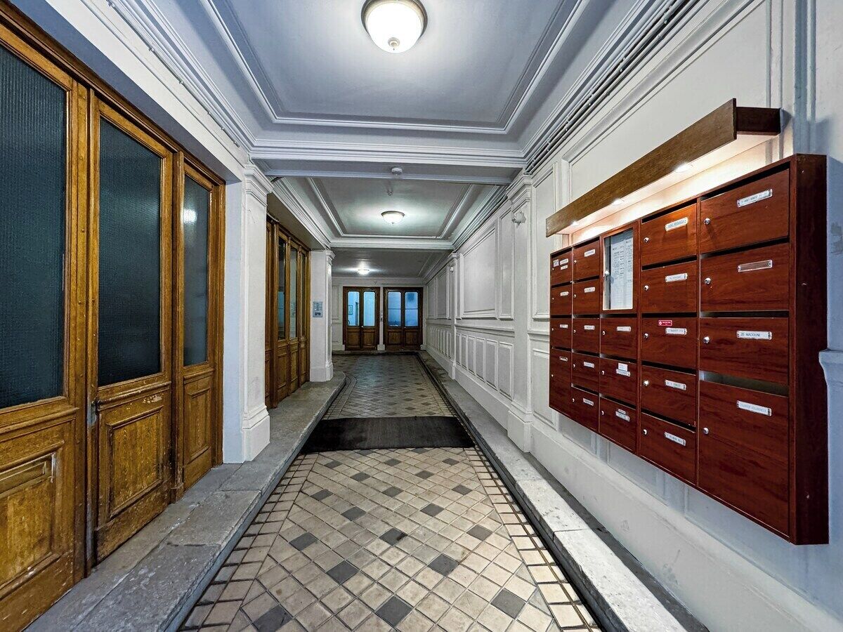 A hallway with wooden doors and a row of wooden mailboxes.