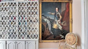 A room with a white bookshelf, a framed portrait, and a vintage chair. - Parisian Home | 2 chambres | Marais - Bastille (Paris)