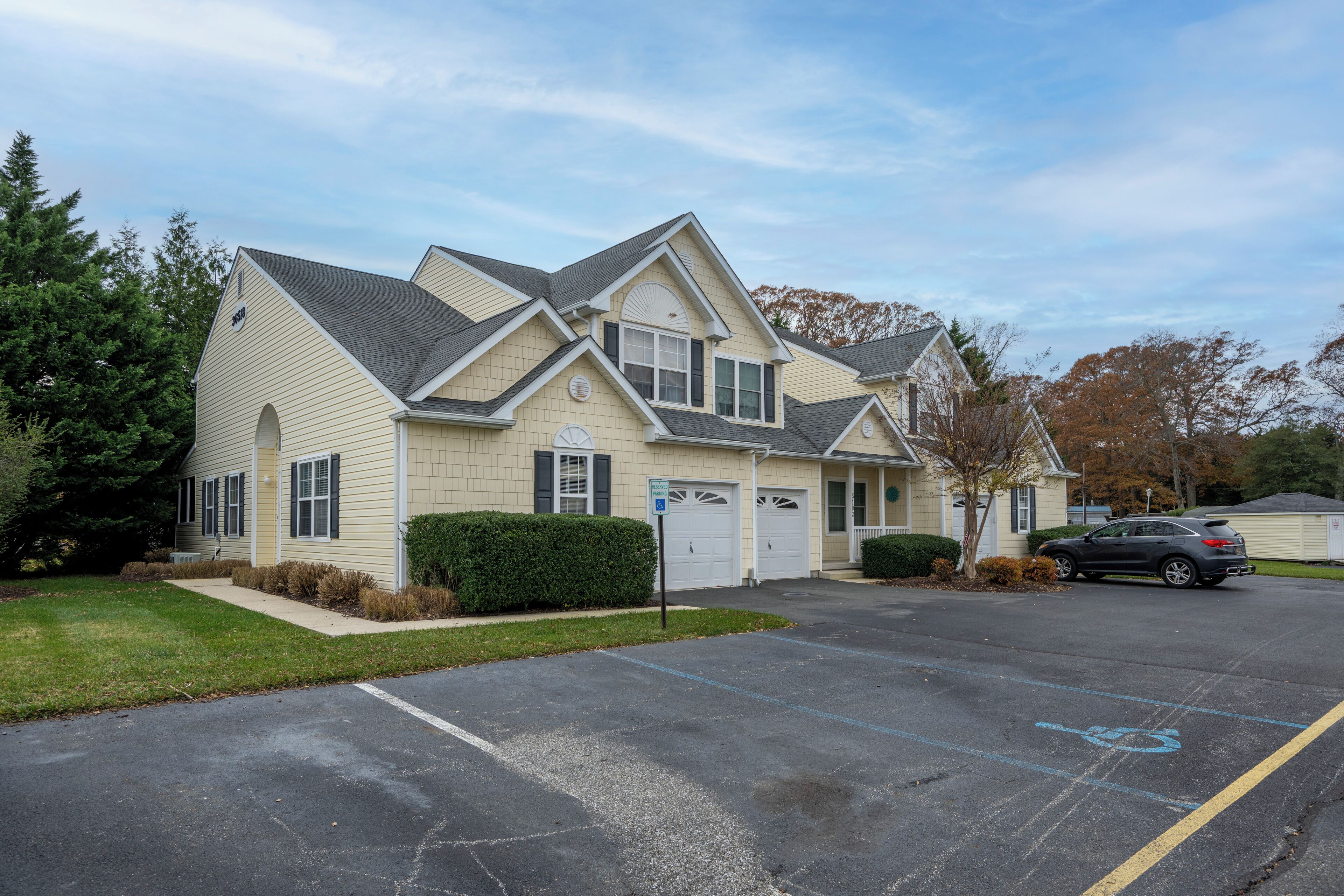 A two-story house with a garage, a driveway, and a parking space marked with a wheelchair symbol.