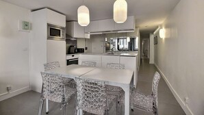 A modern kitchen with white cabinetry, a central island, and pendant lighting. - Parisian Home | 2 chambres | Sentier - Bonne Nouvelle (Paris)