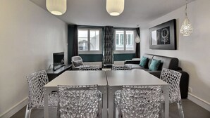 A modern dining area with a long table, clear chairs, and pendant lighting. - Parisian Home | 2 chambres | Sentier - Bonne Nouvelle (Paris)
