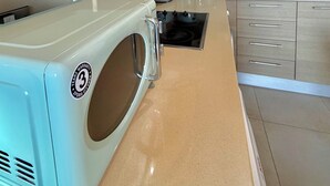 Una cocina moderna con gabinetes de madera, un microondas integrado, una cafetera y un lavamanos.
