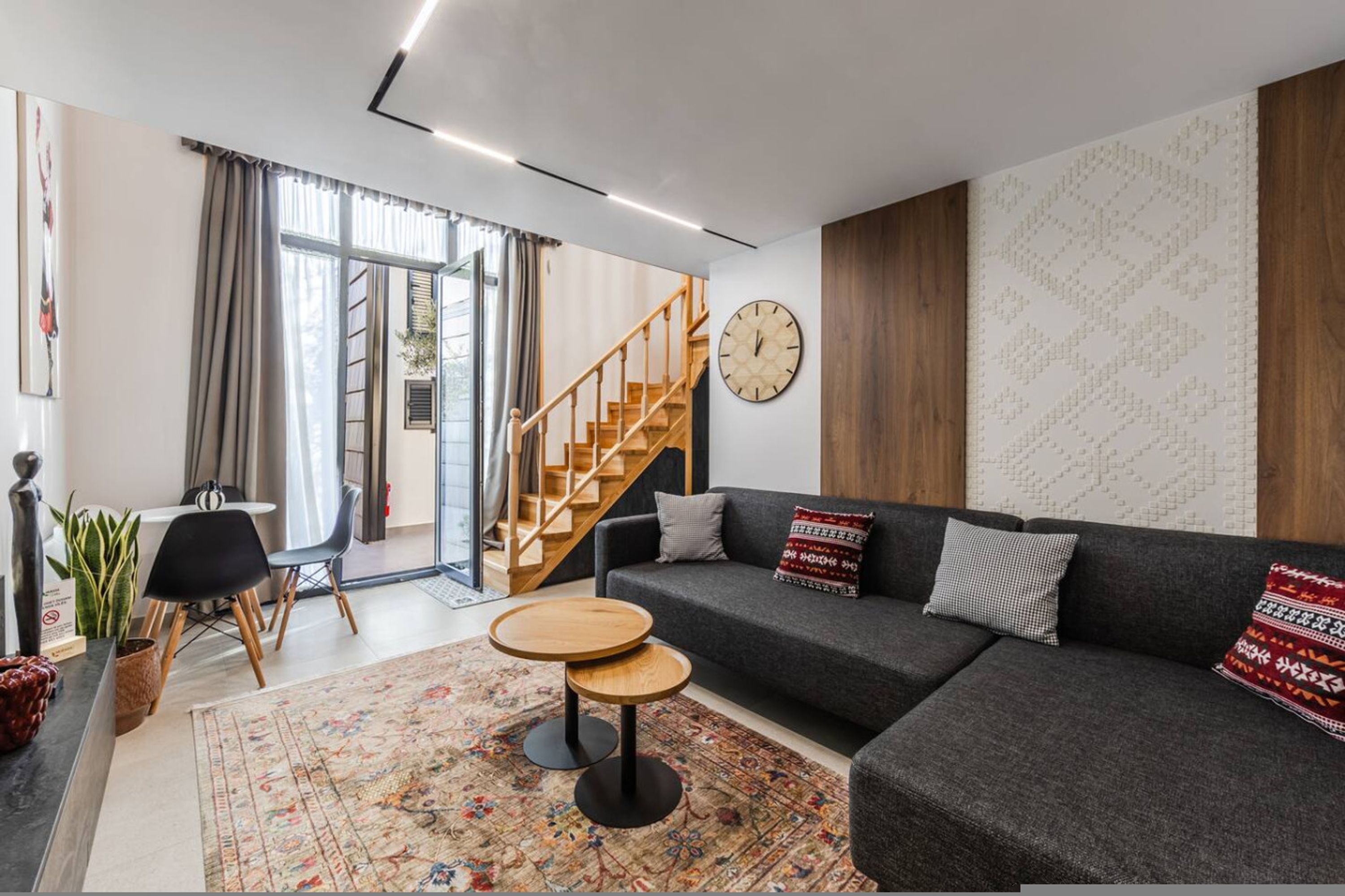 A modern living room with a gray sofa, wooden coffee table, and a staircase leading to an upper level.