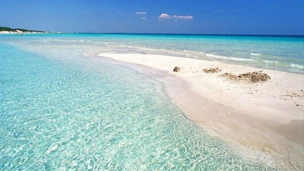 Uma praia com águas turquesa cristalinas e areia branca.