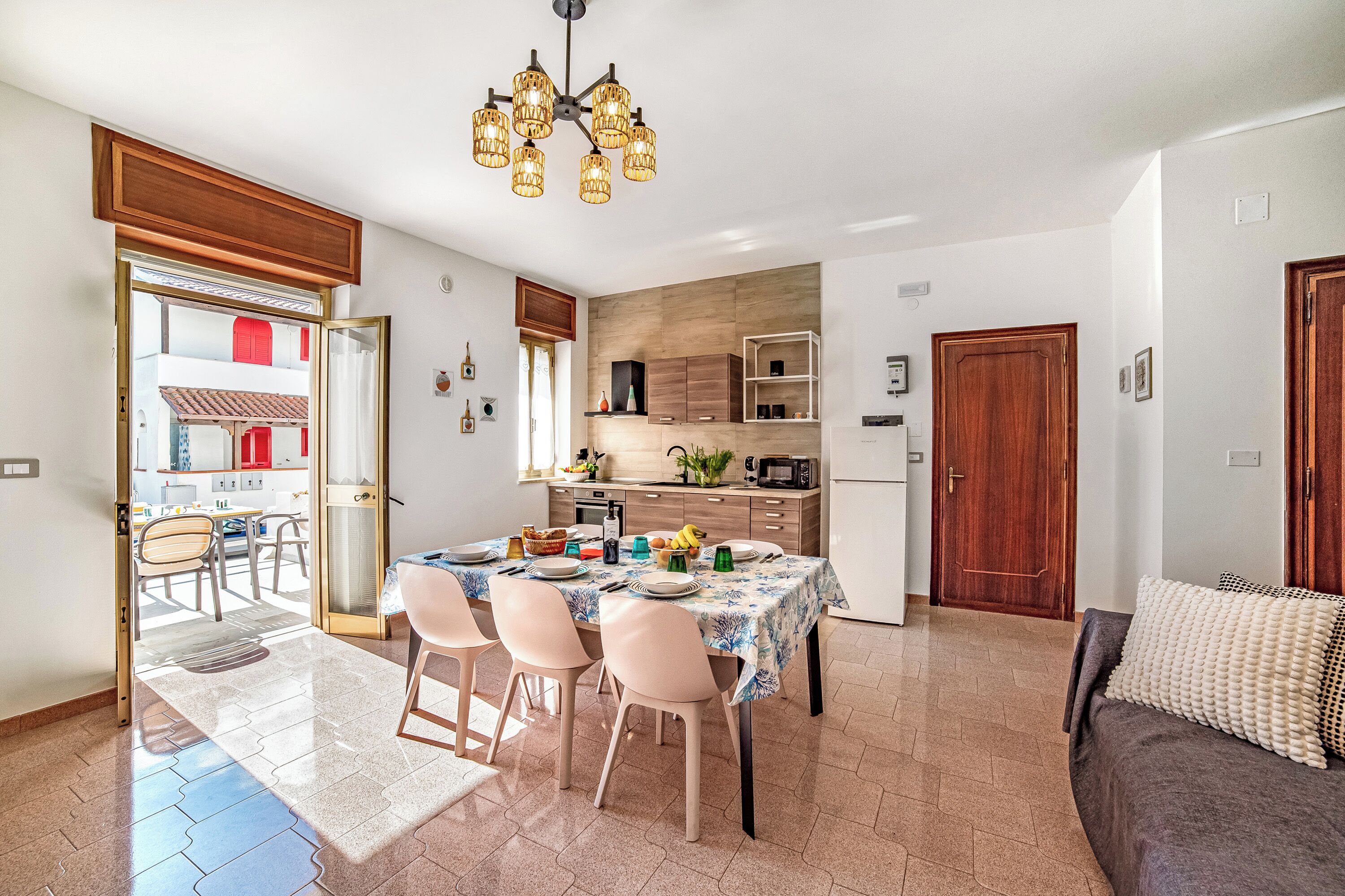 A modern kitchen with a dining area, a sofa, and a view of the outside.