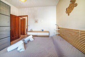 Ein Hotelzimmer mit einem Bett, einem Holzschrank, einem Schminktisch mit Spiegel und einem Wandbild.
