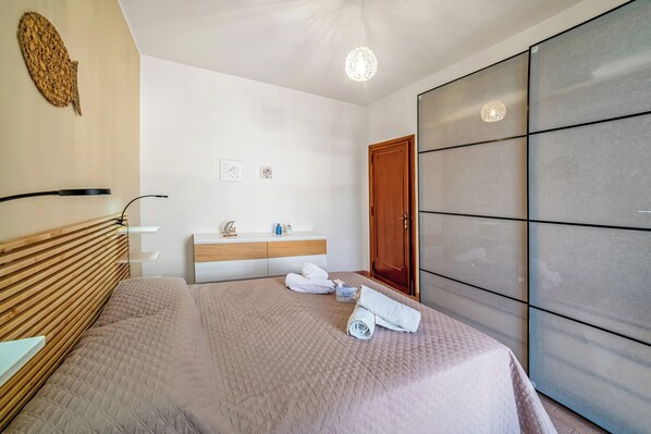 Ein modernes Schlafzimmer mit Bett, Nachttisch und Kleiderschrank.