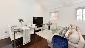 Ein modernes Wohnzimmer mit Glastisch, einer Couch, einem Fernseher und einem Oberlicht.