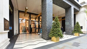 Entrada de un hotel con diseño moderno, que destaca por sus amplias columnas y suelo de baldosas.