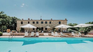 Un edificio in pietra con piscina e lettini.