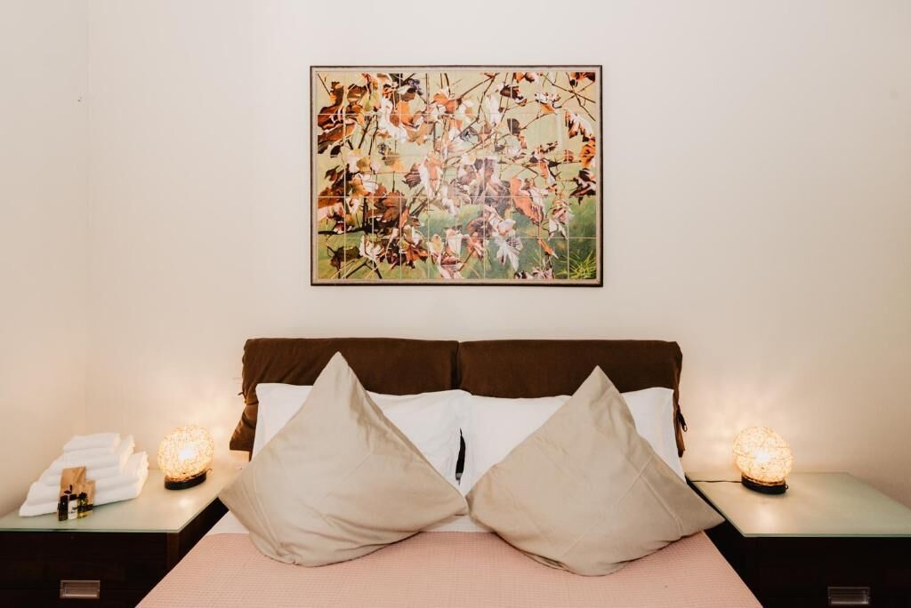 Une chambre d’hôtel comprenant un lit, deux tables de chevet, un tableau accroché au mur et deux lampes de table.