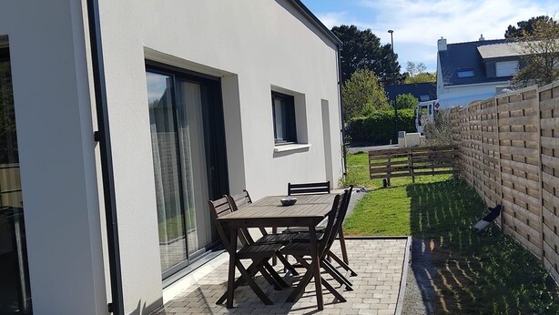 Una casa moderna amb un patí, una taula de menjador i cadires.