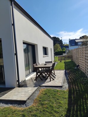 Uma casa moderna com um pátio, uma mesa de jantar e cadeiras.