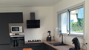 Una cuina moderna amb una illa central, forn integrat, microones i campana extractora negra.